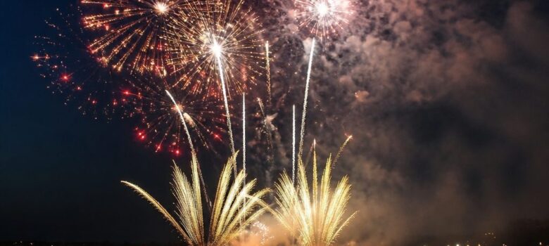 Bouquets rouges et dorés avec fumée au-dessus d’une baie devant les spectateurs