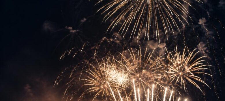 spectacle de drones ou feu d artifice quel format choisir pour son v nement 1 - Spectacle de drones ou feu d’artifice : quel format choisir pour son événement ? - Pyrotechnie.com – Feux d’artifice et culture pyrotechnique Grand bouquet blanc et doré au-dessus d’un front de mer observé par la foule